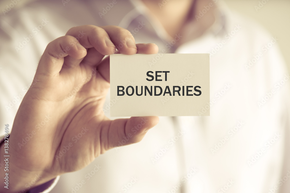 Businessman holding SET BOUNDARIES message card Businessman holding SET BOUNDARIES message card