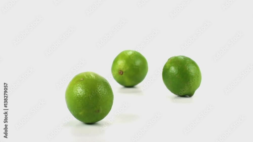 Three limes tumble and fall in slow motion onto a white cyc Three limes tumble and fall in slow motion onto a white cyc