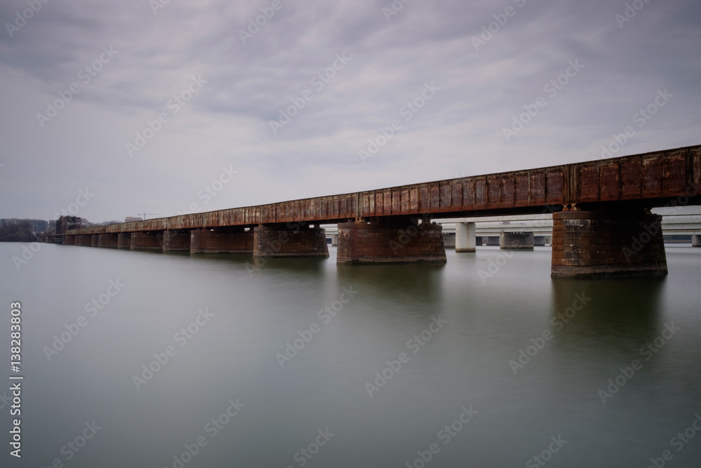 Rusty train bridge over water on a cloudy day Rusty train bridge over water on a cloudy day