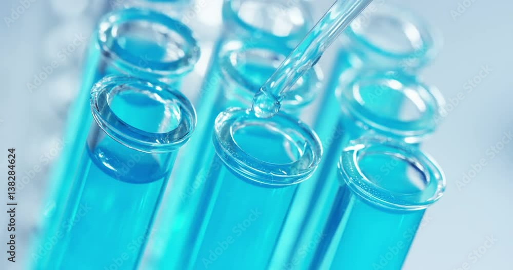 In a laboratory, a scientist with a pipette analyzes a colored liquid to extract the DNA and molecules in the test tubes. Concept: research, biochemistry, nature, pharmaceutical medicine In a laboratory, a scientist with a pipette analyzes a colored liquid to extract the DNA and molecules in the test tubes. Concept: research, biochemistry, nature, pharmaceutical medicine