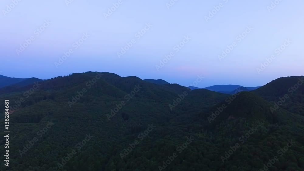 View from the bird's-eye view on the top of the wooded green mountains at sunset. Beautiful bright sky. View from the bird's-eye view on the top of the wooded green mountains at sunset. Beautiful bright sky.