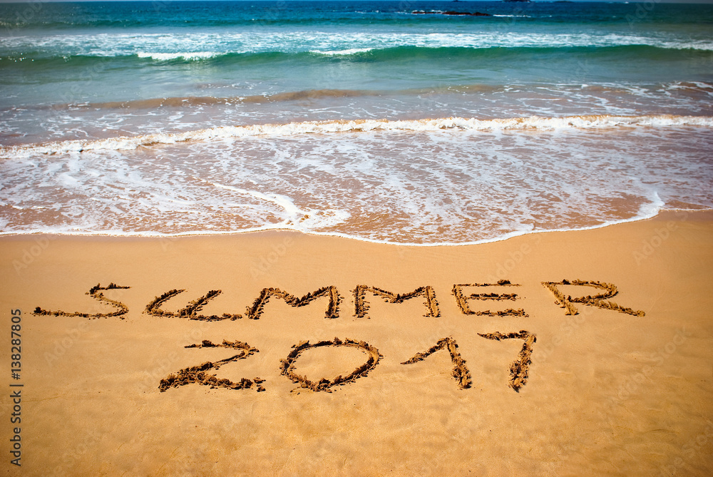 Fototapeta premium Inscription on wet sand Summer 2017. Concept photo of summer vacation on the tropical island ocean beach.