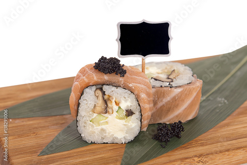 Sushi rolls on wooden Board with leaves of leeks and black sign for logo and name photo