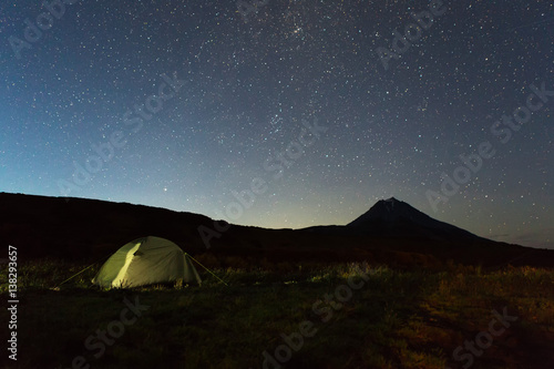Tourist tent against night sky and Vilyuchinsky stratovolcano. Brookvalley Spokoyny at the foot of outer north-eastern slope of caldera volcano Gorely.