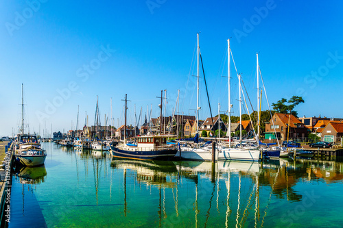 Sail boats and motor boats moored in a part of the harbor overtaken by algae in the historic fishing village of Urk in the Netherlands