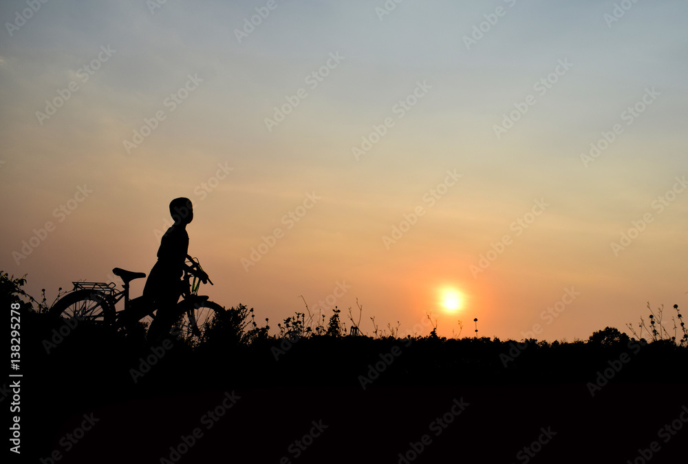 Silhouette boy and bicycle Background sunset