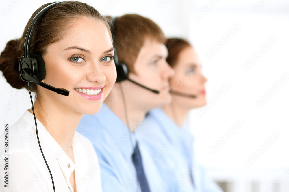 Call center operators. Focus at brunette business woman in headset Call center operators. Focus at brunette business woman in headset