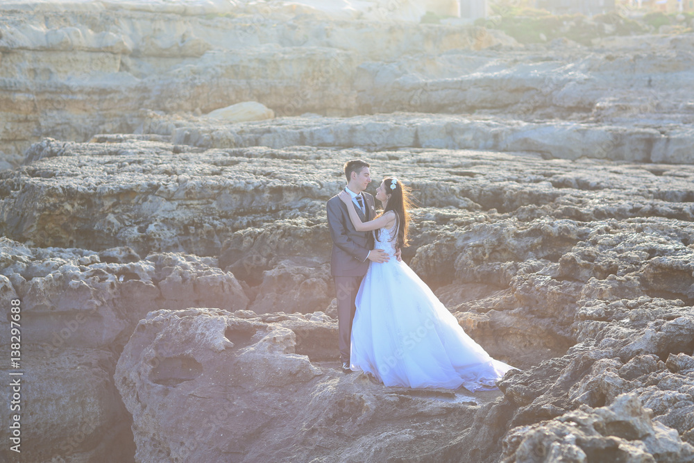 Groom and bride on the rocks near the sea Groom and bride on the rocks near the sea