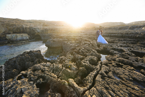 Groom and bride on the rocks near the sea