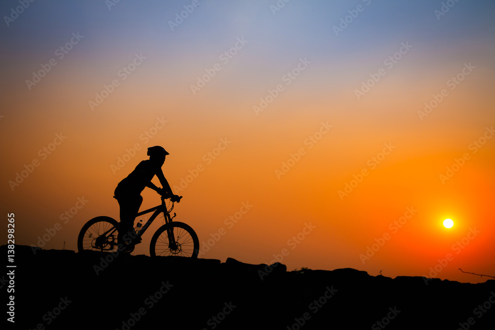 Obraz premium Silhouette of young man cyclist on sunset.