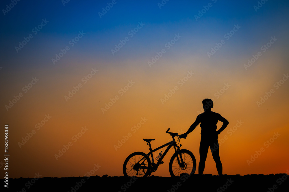 Fototapeta premium Silhouette of young man cyclist on sunset.
