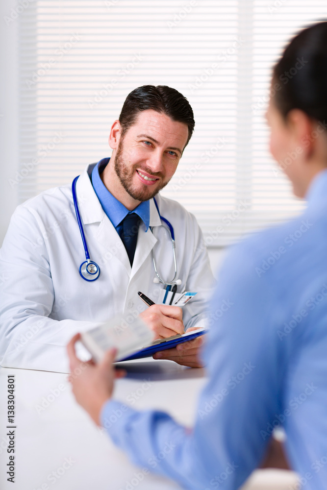 Doctor smiling while writing prescription Doctor smiling while writing prescription