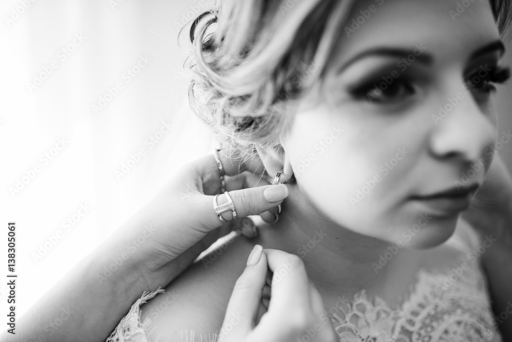 Bridesmaid helped to wear earring for bride on wedding day. Black and white photo.