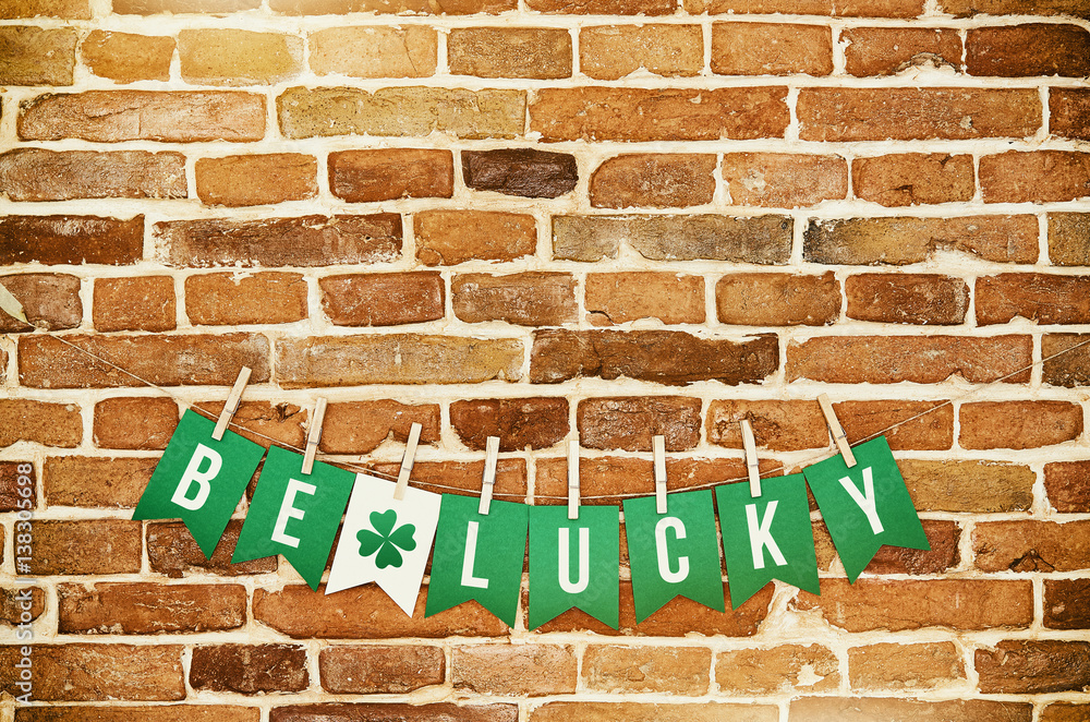 BE LUCKY handmade garland letters on rustic orange wall background. Bright St. Patricks day holiday potcard, banner, greeting card, poster template. Irish national colors. Green clover leaf. BE LUCKY handmade garland letters on rustic orange wall background. Bright St. Patricks day holiday potcard, banner, greeting card, poster template. Irish national colors. Green clover leaf.