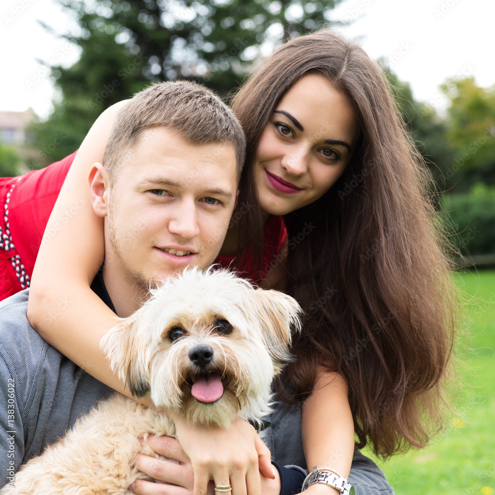 Young couple with puppy. Portrait of attractive happy smiling young woman and man holding cute little dog, summer park outdoor. Young couple with puppy. Portrait of attractive happy smiling young woman and man holding cute little dog, summer park outdoor.