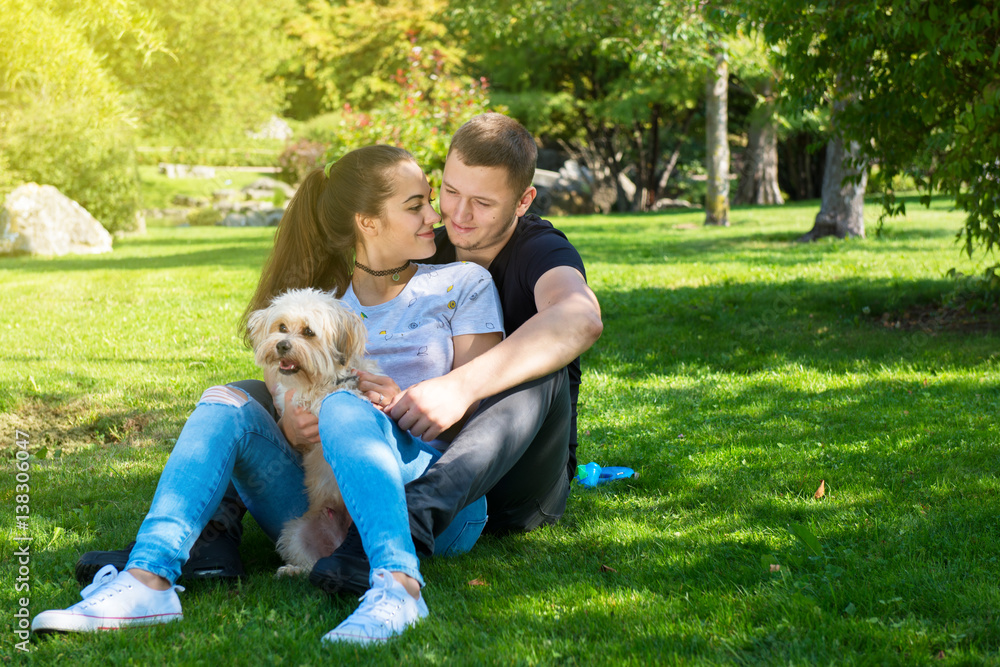 Obraz premium Young couple with puppy. Portrait of attractive happy smiling young woman and man holding cute little dog, summer park outdoor.