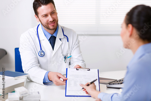 Doctor asking a patient to sign paperwork