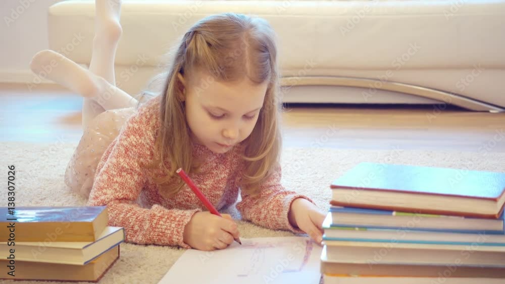 Cute little child girl laying on floor and learning with books at home Cute little child girl laying on floor and learning with books at home