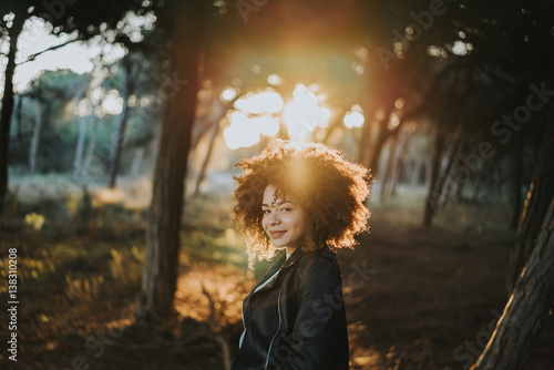 Portrait of smiling woman standing outdoors in sunbeam