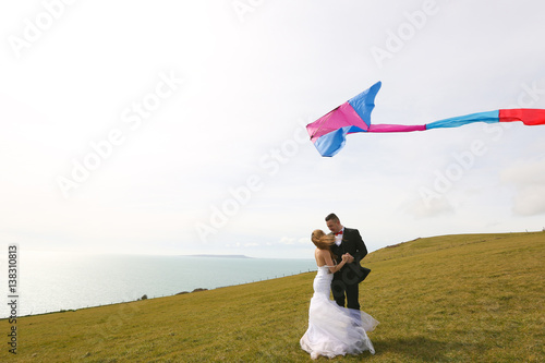Groom and bride having fun with a kite