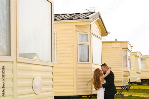 Groom and bride posing near white houses