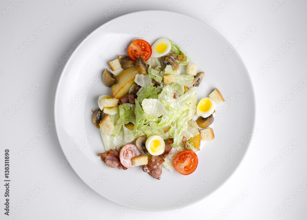 Salad with fried bacon and vegetables on a white plate on a white background Salad with fried bacon and vegetables on a white plate on a white background