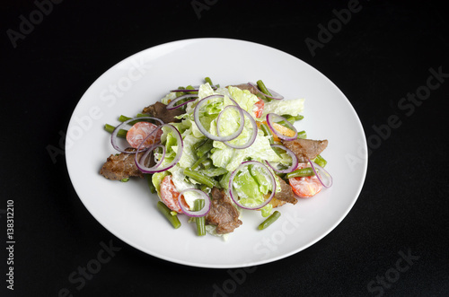 Salad with beef roast beef and vegetables on a black background