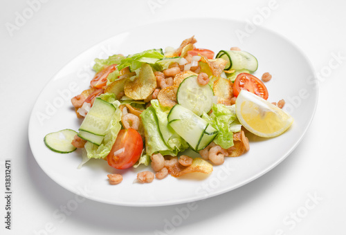 Salad from seafood and vegetables on a white plate
