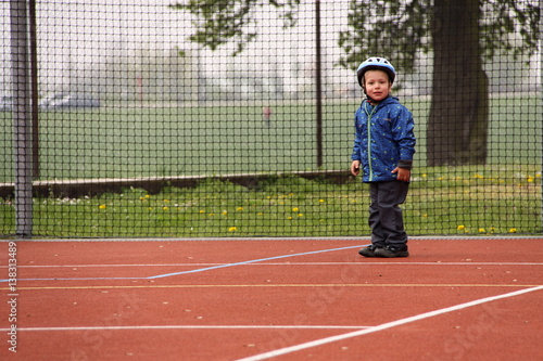 Boy in bicycle helmet on the red playground © ondrejschaumann