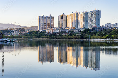 Residential buildings and ferris wheel water reflection in China