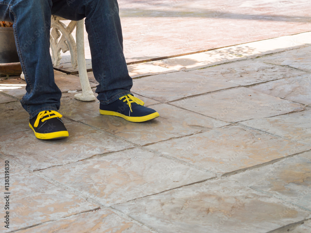 closeup man legs wear blue jeans pants and sneakers shoes space for text closeup man legs wear blue jeans pants and sneakers shoes space for text