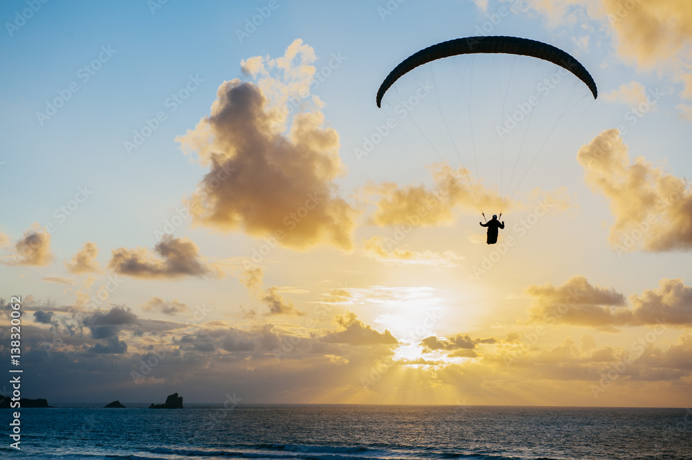 Silhouette of person flying on the parachute over the sea in sunset lights. Silhouette of person flying on the parachute over the sea in sunset lights.