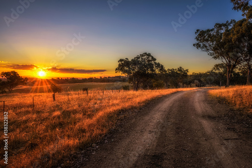 Countryside landscape with rural dirt road at sunset in Australia © Nick Fox