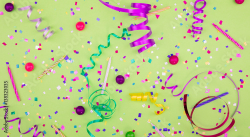 Colorful party attributes with streamers, confetti and horns over GREEN background. Flat lie. High resolution photo.