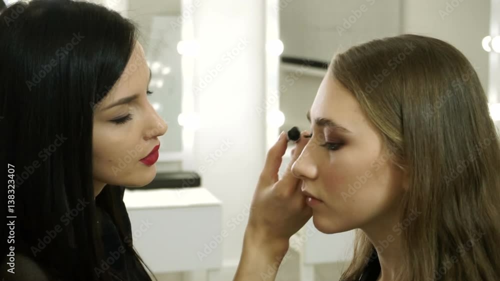 Professional female make-up artist applying black mascara on the long eyelashes of young pretty girl. HD Professional female make-up artist applying black mascara on the long eyelashes of young pretty girl. HD