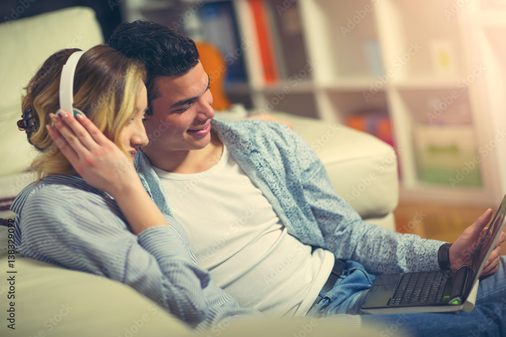 Young couple relaxing on the couch with laptop in their living room at home Young couple relaxing on the couch with laptop in their living room at home