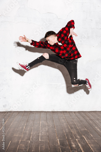 Vertical image of Young Hipster jumping in studio