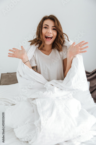 Pretty lady dressed in white t-shirt sitting on bed