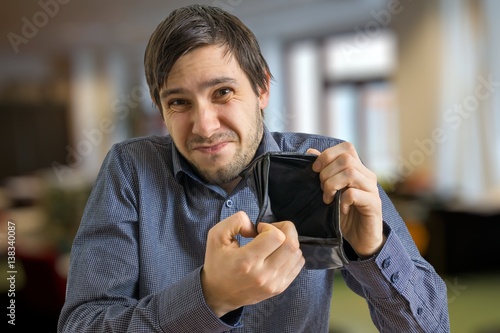 Canvas Print Young man has no money ans is showing his empty wallet.
