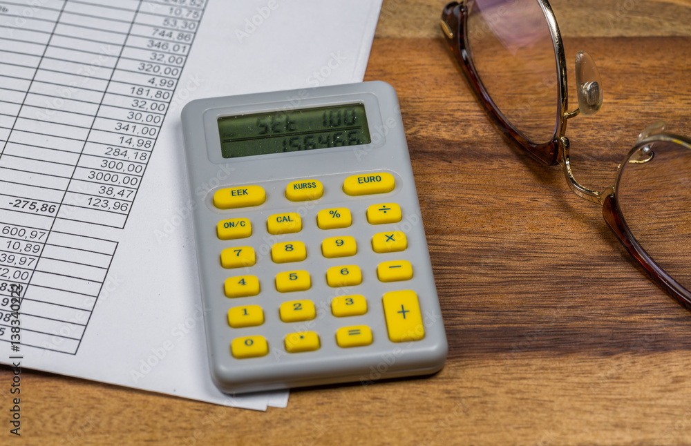 Side view of work desk with eye glasses,document and calculator Side view of work desk with eye glasses,document and calculator
