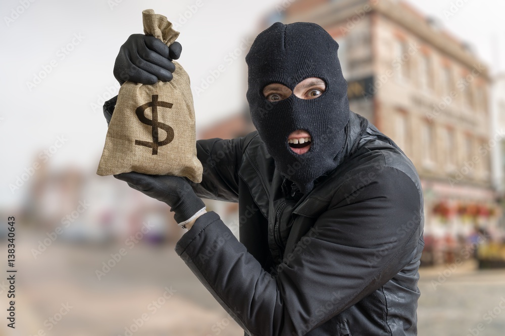 Happy robber is showing stolen bag full of money. Stock Photo | Adobe Stock