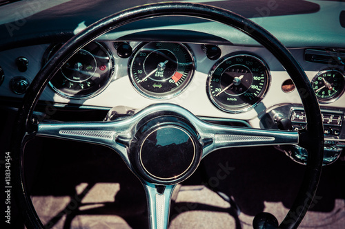 Closeup view of a black steering wheel and a dashboard