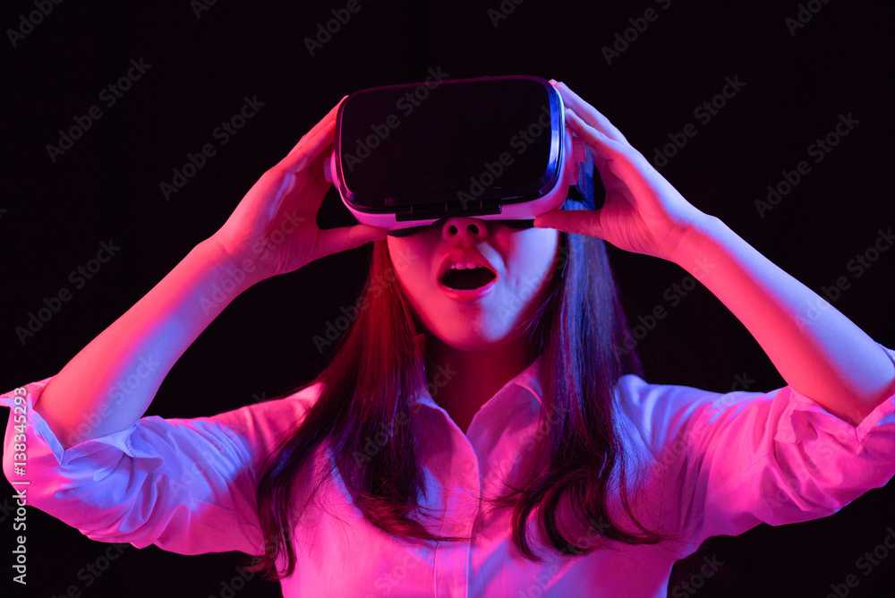 Asian Chinese young woman using virtual reality smart glasses play game.low key photo Asian Chinese young woman using virtual reality smart glasses play game.low key photo