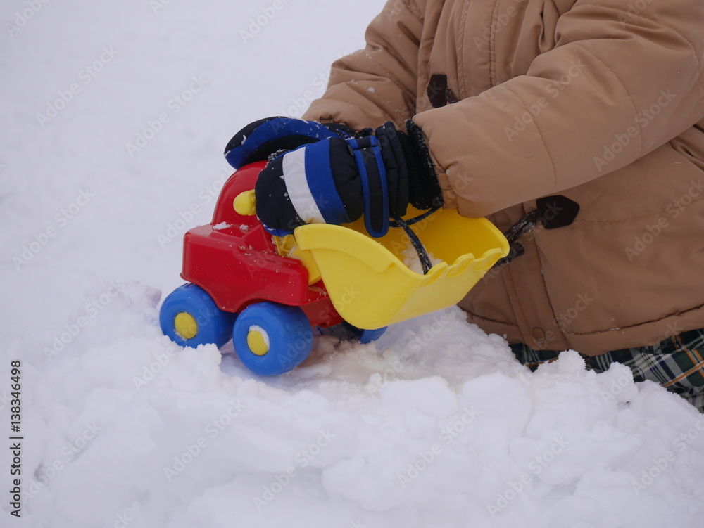 Obraz premium A child playing in snow with toys