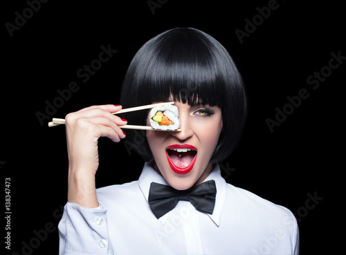 Young woman holding sushi in front of eye