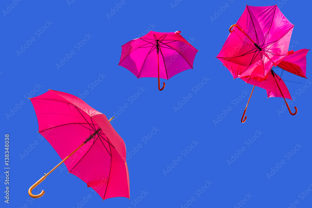 ombrelles roses chahutées et emportées par le vent sur fond de ciel bleu 
