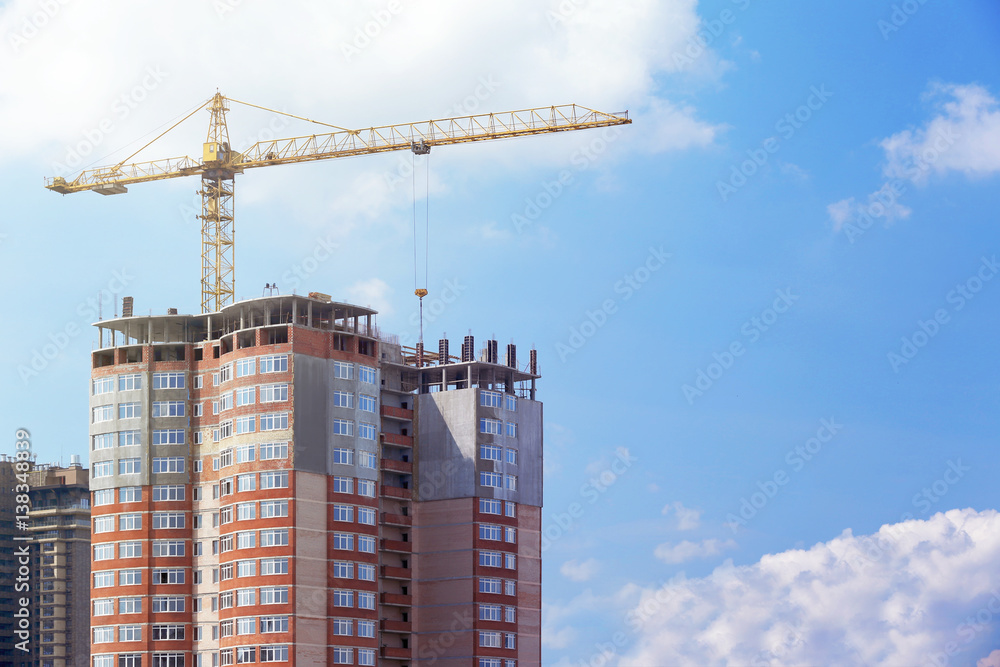Construction crane and unfinished building with blue sky on background Construction crane and unfinished building with blue sky on background