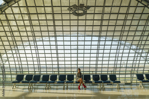 Beautiful young woman sits on the bench in an airport and waits a flight photo