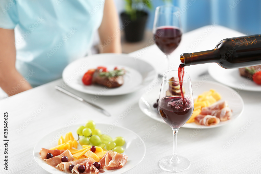 Pouring red wine into glass from bottle in restaurant