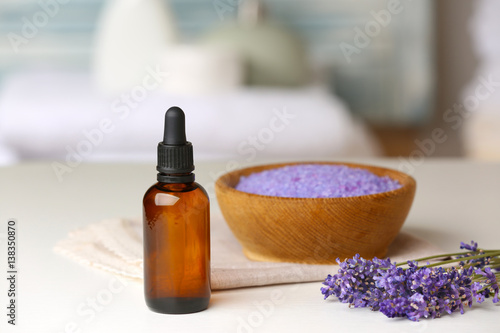 Bottle of essential oil with lavender and sea salt on background